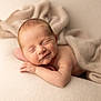 newborn, baby, sleeping, smiling, blanket, soft_texture, cozy, infant, peaceful, resting, skin, head, hand, portrait, closeup, warm_lighting, fabric, cute, child, indoors