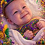 baby, towel, mardi_gras, jester_hat, mask, beads, confetti, celebration, smile, festive, purple, green, gold, feathers, crown, happy, portrait, child, colorful, party