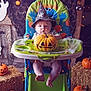 William joined the competition — help win amazing prizes! baby, high_chair, pumpkin, halloween, wizard_hat, jack_o_lantern, decorations, string_lights, hay_bales, cutouts, ghost, bat, floor, wooden_door, lantern, orange, costume, indoor, infant, festive