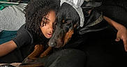 Baki is registered to the contest to win money with this photo: bed, black_dog, blanket, bunny_ears, casual, comfort, cozy, cuddling, curly_hair, cute, dog, home, hugging, indoors, large_dog, person, plant, plush_toy, relaxing, stuffed_bear