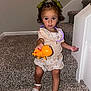 toddler, child, toy, orange_toy, stairs, carpet, green_bows, hair_accessories, necklace, glow_stick, sitting, curious, indoor, white_sandals, floral_skirt, short_sleeve_top, young_child, playful, looking_at_camera, home