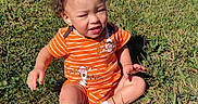 Zayden is registered to the contest to win money with this photo: toddler, child, baby, sitting, grass, outdoor, neighborhood, residential_street, orange_outfit, striped_clothing, short_sleeves, socks, sunlight, portrait, facial_expression, parked_cars, houses, lawn, leaf, daytime