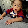 Zayden joined the competition — help win amazing prizes! toddler, child, baby, portrait, indoors, home, sitting, curious, wide_eyes, open_mouth, brown_hair, red_shirt, gray_fabric, hands, face, dresser, electronic_device, household, close_up, casual_photo
