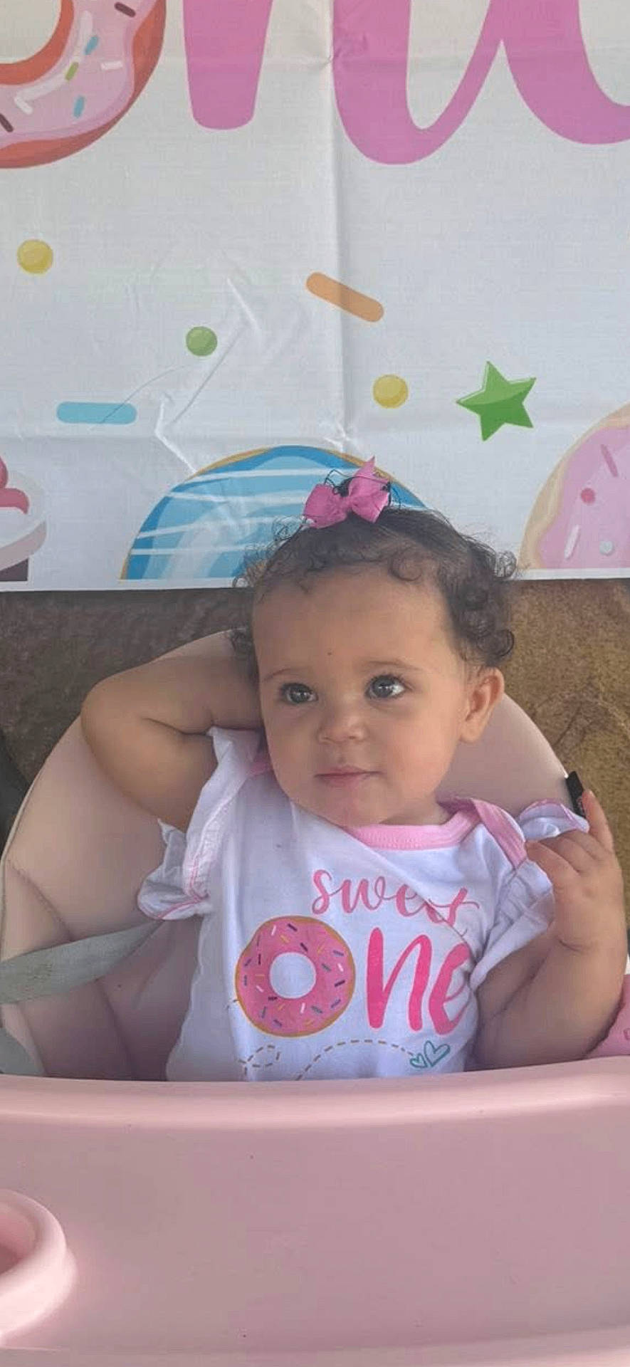 Nyah joined the competition — help win amazing prizes! baby, birthday_theme, celebration, child, colorful_sprinkles, curly_hair, cute, donut_graphic, festive, green_star, high_chair, indoor, pink_bow, pink_high_chair, portrait, seated, sweet_one, toddler, white_shirt, young_child