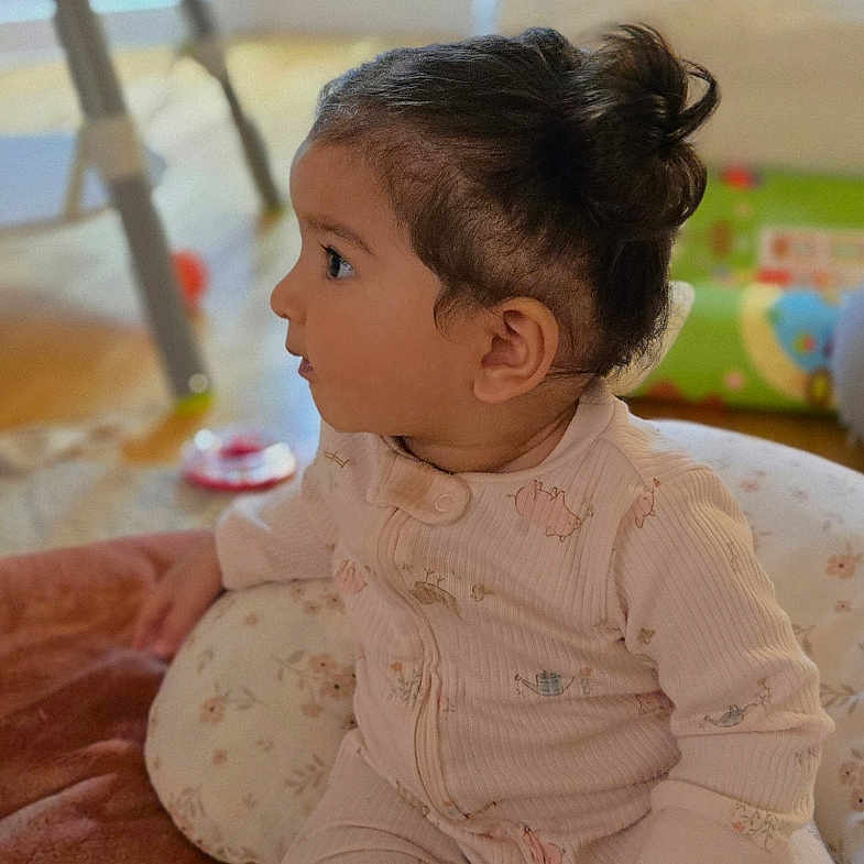 Anayra joined the competition — help win amazing prizes! animal_prints, baby, blanket, child, cozy, curly_hair, cushion, face, floor, foot, furniture, hand, indoors, pajamas, play_area, profile, sitting, soft_light, toy, young_child