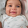 baby, smiling, blue_eyes, curly_hair, onesie, rainbow_pattern, blanket, closeup, infant, cute, happy, child, portrait, skin, face, lying_down, soft_texture, indoors, young, person