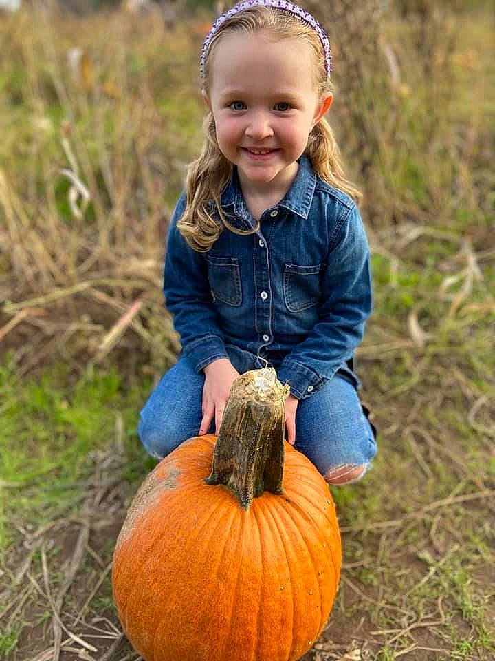 Josie joined the competition — help win amazing prizes! calabaza, eye, face, facial_expression, fruit, gourd, grass, hair, hand, happy, head, human_body, jeans, joy, people_in_nature, person, photograph, plant, pumpkin, smile