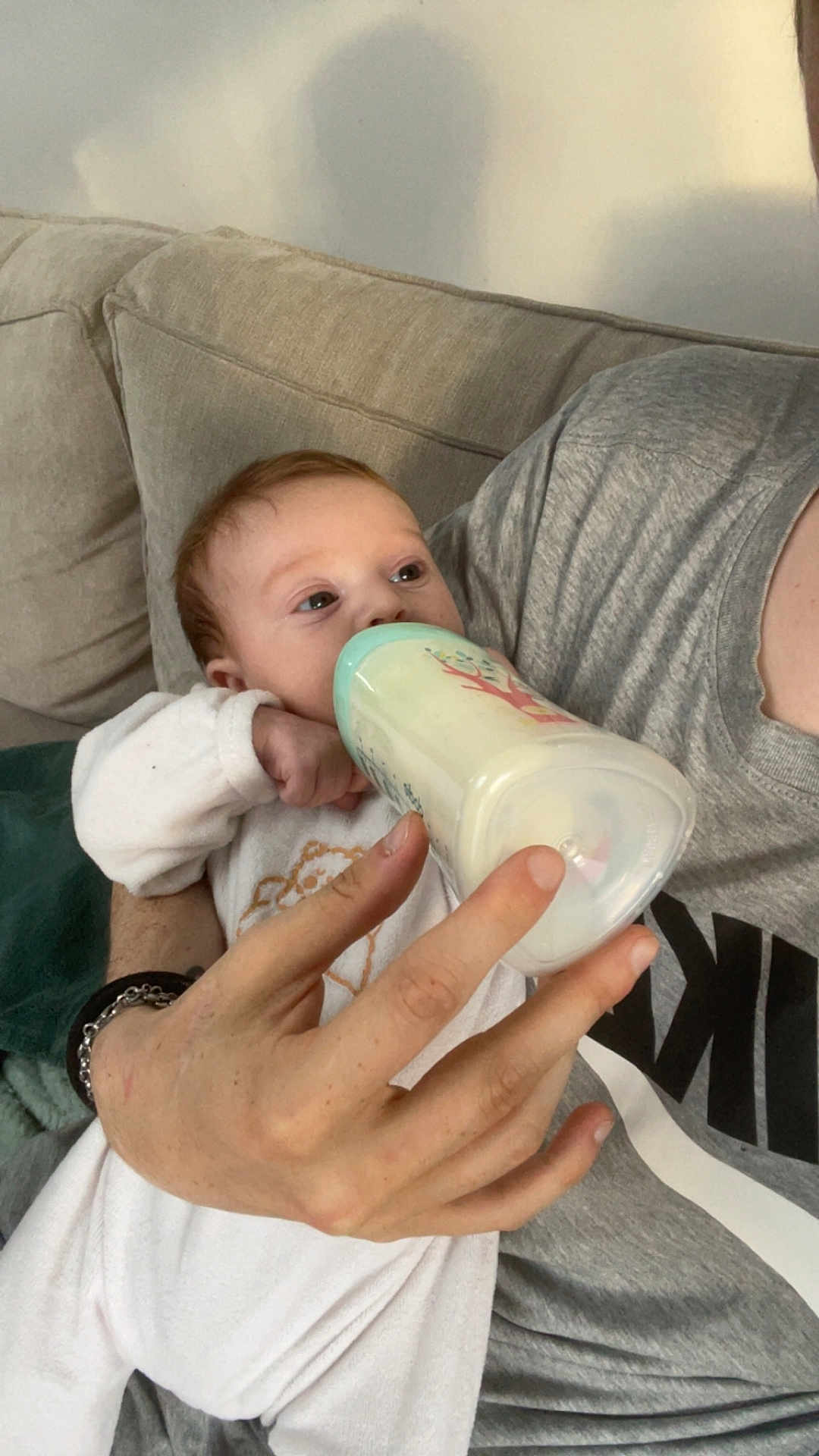 Léna a rejoint le concours — aidez-le/la à gagner de superbes lots ! baby, bottle, feeding, hand, person, couch, clothing, sleeve, face, infant, milk, adult, holding, sitting, comfort, indoor, relaxation, casual, white_clothing, bracelet