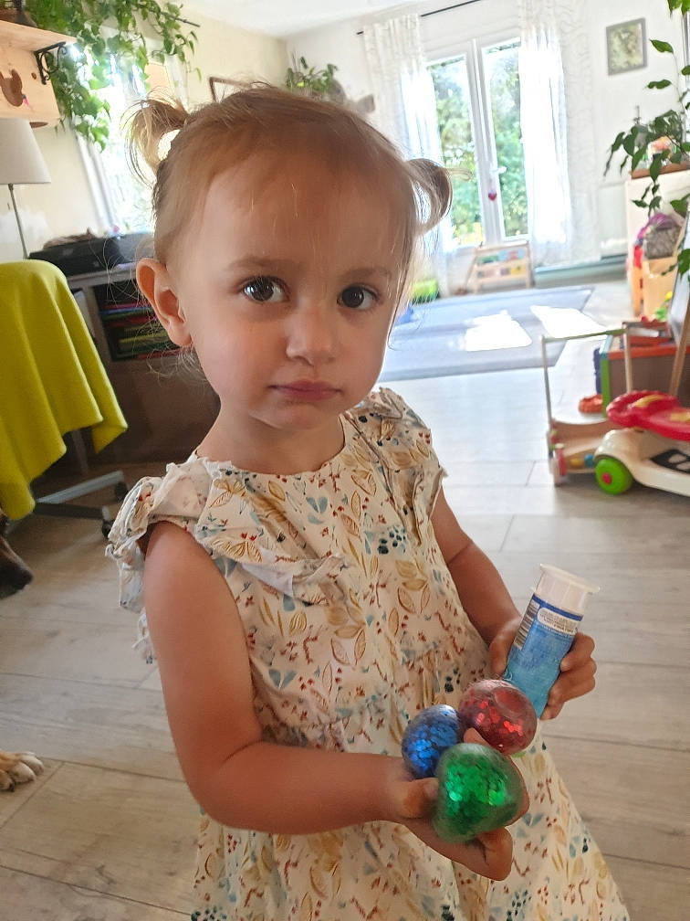 Jeanne a rejoint le concours — aidez-le/la à gagner de superbes lots ! baby_toddler_clothing, bottle, chair, child, dress, flooring, fun, green, happy, houseplant, people, person, photograph, plant, plastic_bottle, standing, summer, toddler, water_bottle, window