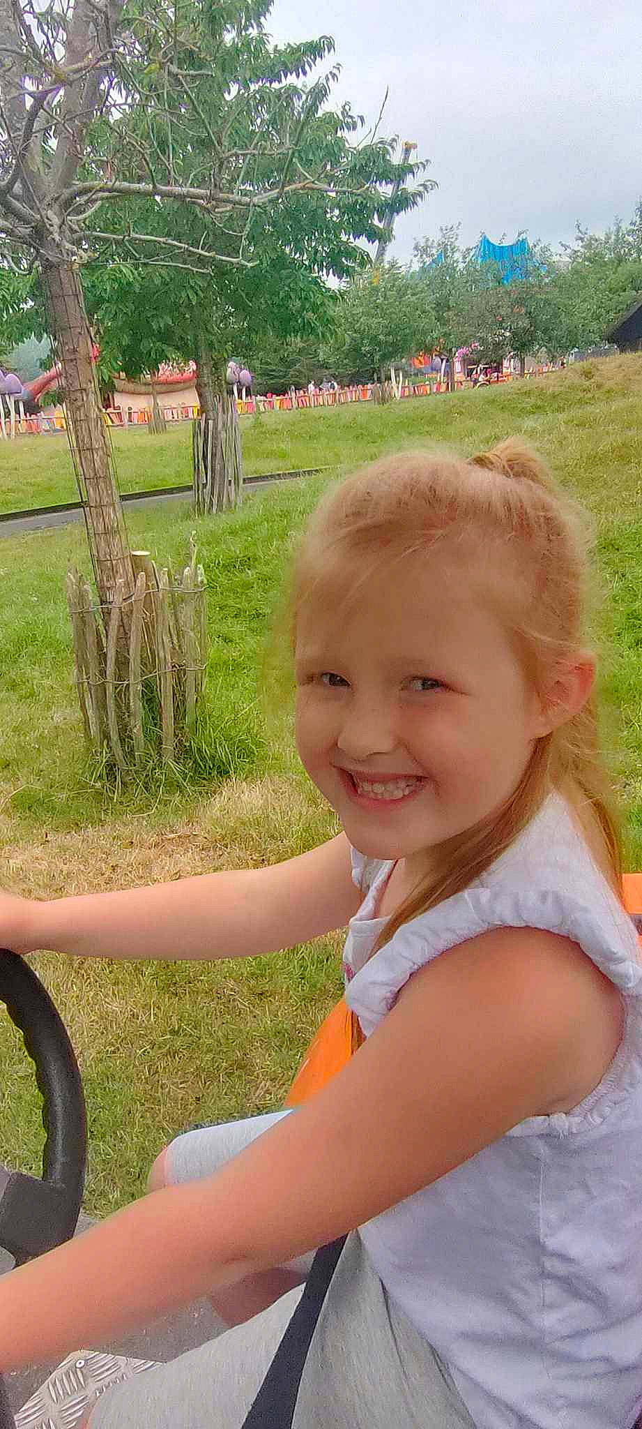 Juline a rejoint le concours — aidez-le/la à gagner de superbes lots ! automotive_tire, child, fun, grass, grass_family, happy, joy, landscape, leisure, people_in_nature, person, plant, recreation, sitting, smile, spring, steering_wheel, summer, toddler, tree