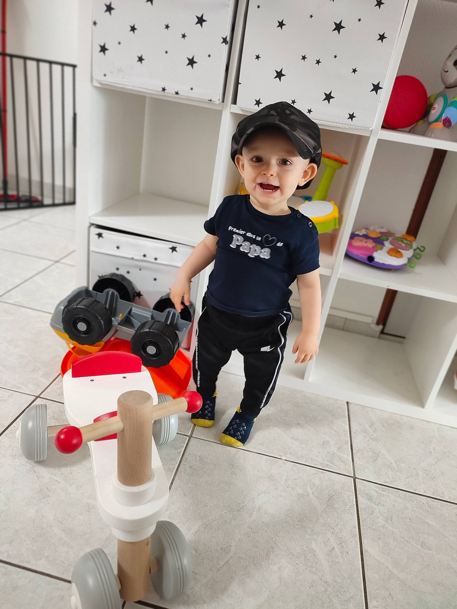Nolan a rejoint le concours — aidez-le/la à gagner de superbes lots ! baby_toddler_clothing, child, cleanliness, fashion_accessory, floor, flooring, hat, headwear, human_leg, knee, luggage_and_bags, person, room, shelf, shoe, sleeve, sneakers, standing, t_shirt, toddler