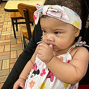 Raniah joined the competition — help win amazing prizes! adult_holding_child, baby, cafe, cartoon_character, chairs, child, curious, dress, earrings, floral_pattern, hand_to_mouth, headscarf, indoor, infant, minnie_mouse, portrait, restaurant, sitting, tables, tile_floor
