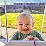 baby, backyard, child, daylight, fence, fun, grass, green_clothing, hand, happy, infant, outdoor, person, playground, portrait, seat, smiling, sunlight, swing, toddler
