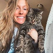 Lilly May joined the competition — help win amazing prizes! animal, casual_clothing, cat, cozy, expression, face, furniture, hand, happy, holding, home, indoor, jewelry, light, long_hair, pet, portrait, smiling, tabby_cat, woman