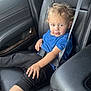 Kyle is registered to the contest to win money with this photo: child, toddler, car_seat, seatbelt, blue_shirt, black_pants, blond_hair, leather_seat, car_interior, window, door_panel, seatbelt_fastened, young_child, sitting, casual_clothing, indoors, curious_expression, messy_face, hand, footwear