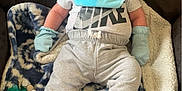 Kyle is registered to the contest to win money with this photo: baby, infant, blanket, blue_mittens, blue_socks, bib, pacifier, nike_shirt, gray_pants, seated, indoor, cute, child, person, soft_toys, cozy, relaxed, young, face, looking