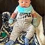baby, infant, blanket, blue_mittens, blue_socks, bib, pacifier, nike_shirt, gray_pants, seated, indoor, cute, child, person, soft_toys, cozy, relaxed, young, face, looking