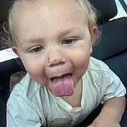Kyle is registered to the contest to win money with this photo: child, toddler, tongue_out, blonde_hair, scratches, white_tshirt, car_seat, playful, closeup, face, hand, cute, messy_hair, indoors, car_interior, person, portrait, happy, baby, expression