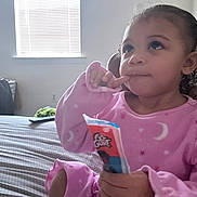 Zhai joined the competition — help win amazing prizes! child, toddler, pajamas, pink_pajamas, snack, bed, window, blinds, remote_control, thoughtful, curly_hair, portrait, indoor, person, food_package, blanket, bedroom, sitting, hand, face