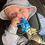 baby, child, blue_eyes, hoodie, car_seat, toy, buckle, straps, seatbelt, infant, cute, chewing, hand, clothing, indoor, light, face, portrait, sitting, young