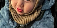 Leo is registered to the contest to win money with this photo: child, toddler, face, expression, clothing, jacket, knit_hat, gloves, winter_wear, blue, brown, portrait, indoor, cute, warm, soft_texture, fuzzy, close_up, smile, seatbelt