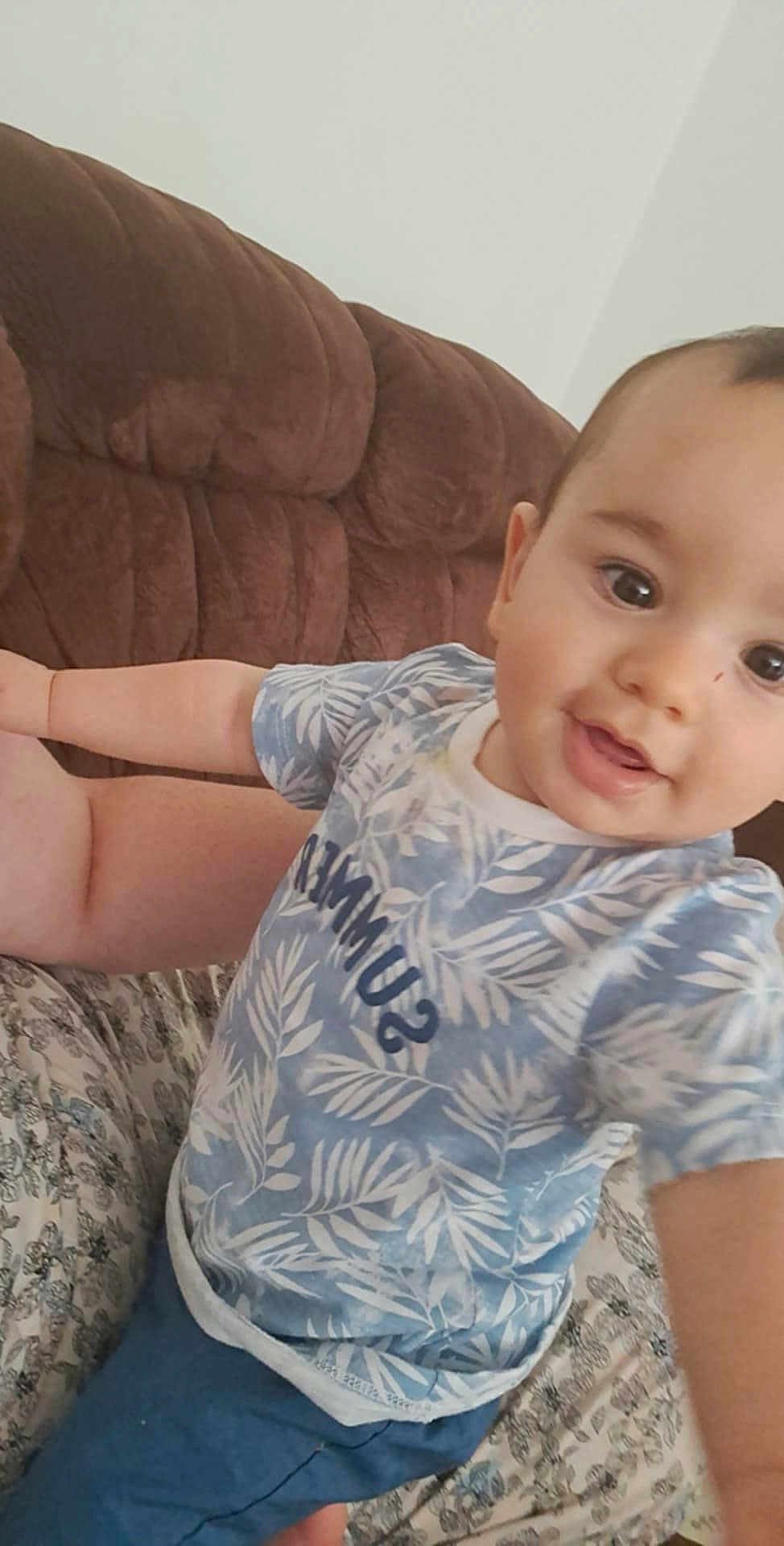 Giuliann participe au concours pour gagner de l'argent avec cette photo : toddler, child, smiling, blue_clothing, patterned_shirt, indoor, sofa, brown_sofa, person, face, happy, curious, baby, short_sleeves, couch, seated, close_up, home, casual, light_skin