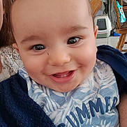 Giuliann a rejoint le concours — aidez-le/la à gagner de superbes lots ! baby, smiling, face, closeup, infant, child, blue_clothing, blanket, indoors, happy, expression, person, cute, eyes, mouth, teeth, head, sitting, toddler, clothing
