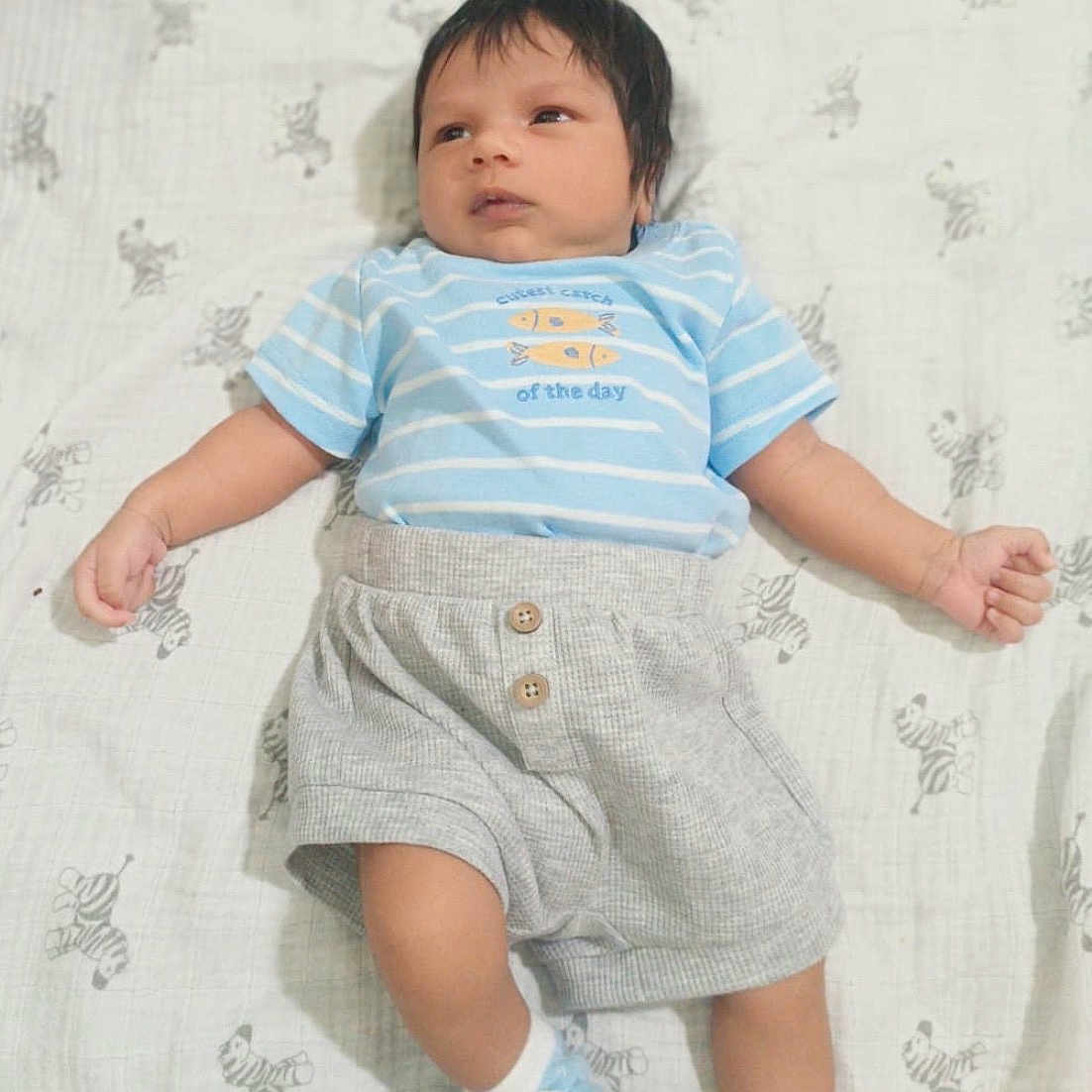 Mannan Ali is registered to the contest to win money with this photo: baby, blue_shirt, child, clothing, cute, gray_shorts, indoors, infant, lying_down, patterned_blanket, person, portrait, resting, sleepwear, small_hands, socks, soft_lighting, striped_shirt, young_child, zebra_pattern