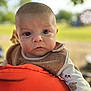 Aaron a rejoint le concours — aidez-le/la à gagner de superbes lots ! baby, infant, face, eyes, bib, clothing, orange, cushion, outdoor, blurred_background, cute, curious, child, portrait, closeup, hedgehog_pattern, mushroom_pattern, soft_light, head, person