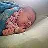 newborn, baby, sleeping, infant, portrait, face, hands, fist, blanket, blue_blanket, pink_clothing, strawberry_pattern, bed, bedding, cozy, indoors, closeup, peaceful, resting, soft_lighting