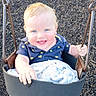 baby, blanket, blue_eyes, child, clothing, cute, daylight, fun, happy, holding, infant, joyful, outdoor, person, playground, seat, short_sleeves, smiling, swing, wood_chips