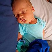 Jackson is registered to the contest to win money with this photo: baby, sleeping, pacifier, blue_onesie, blanket, bed, bedding, infant, child, soft_fabric, peaceful, resting, indoors, closeup, portrait, person, skin, head, hand, nap