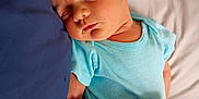 Jackson is registered to the contest to win money with this photo: baby, bed, bedding, blanket, blue_onesie, child, closeup, hand, head, indoors, infant, nap, pacifier, peaceful, person, portrait, resting, skin, sleeping, soft_fabric