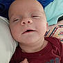 Jackson joined the competition — help win amazing prizes! baby, infant, face, skin, hand, clothing, maroon_shirt, text_on_clothing, fabric, pillow, cushion, sleepy, closeup, indoors, person, newborn, soft_texture, resting, young_child, head