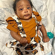 Janovia joined the competition — help win amazing prizes! baby, infant, child, orange_clothing, butterfly_pattern, bed, blanket, pillow, cute, fist, lying_down, expression, indoors, soft_toys, pacifier, comfortable, young, person, face, portrait