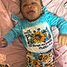 baby, blanket, blue_clothing, child, cute, expression, face, happy, indoor, infant, leopard_print, lying_down, patterned_clothing, person, pink_blanket, playful, smiling, sunflower, toddler, young_child