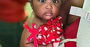 Janovia is registered to the contest to win money with this photo: baby, child, infant, polka_dot, red_dress, person, holding, close_up, face, indoors, cute, adorable, expression, portrait, skin, hair, bow, clothing, hand, focus