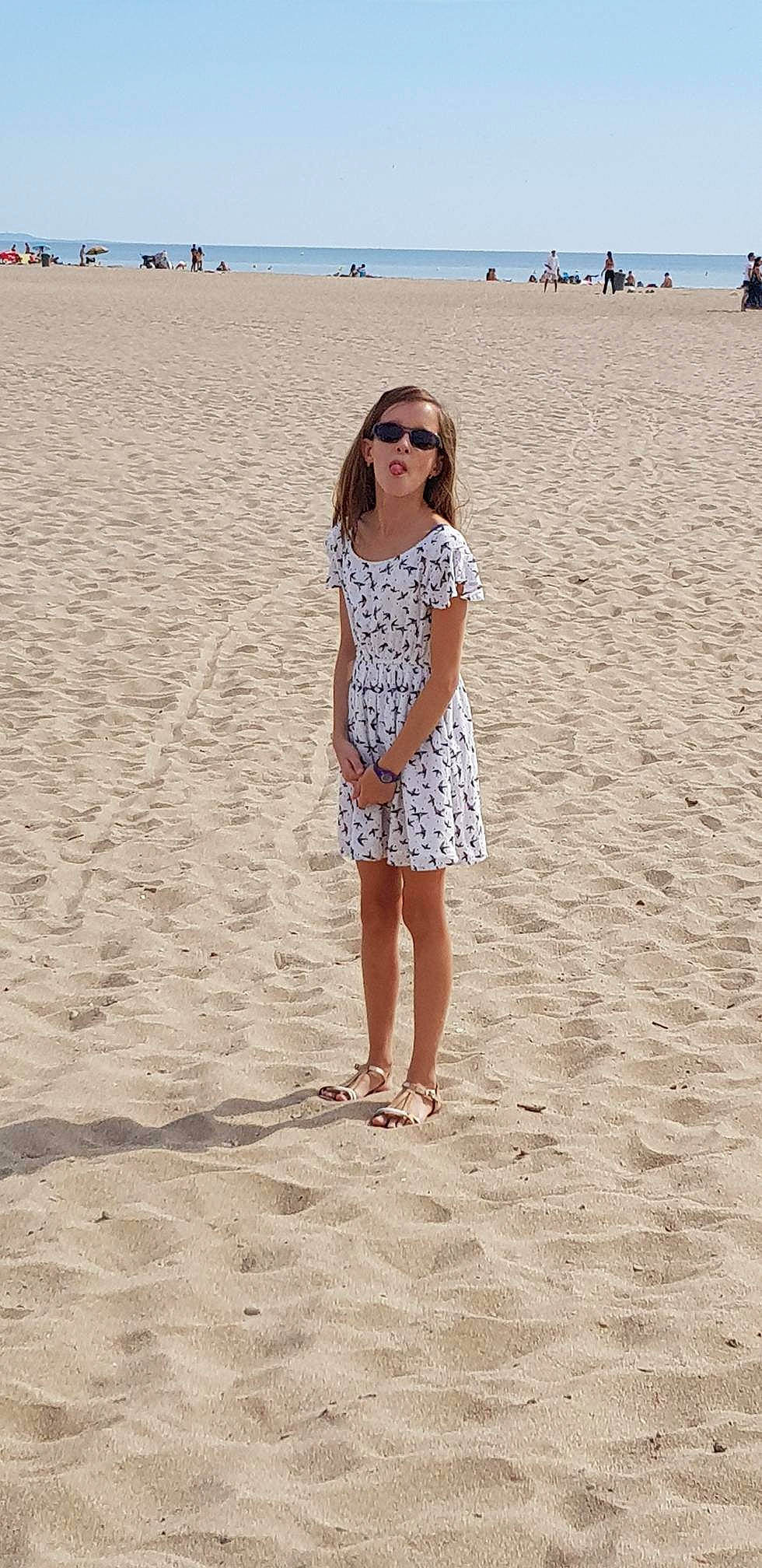 Cassandra participe au concours pour gagner de l'argent avec cette photo : beach, beige, clothing, dress, fashion, fawn, fun, pattern, person, sand, sea, shoulder, sleeve, summer, sunglasses, tourism, vacation, white