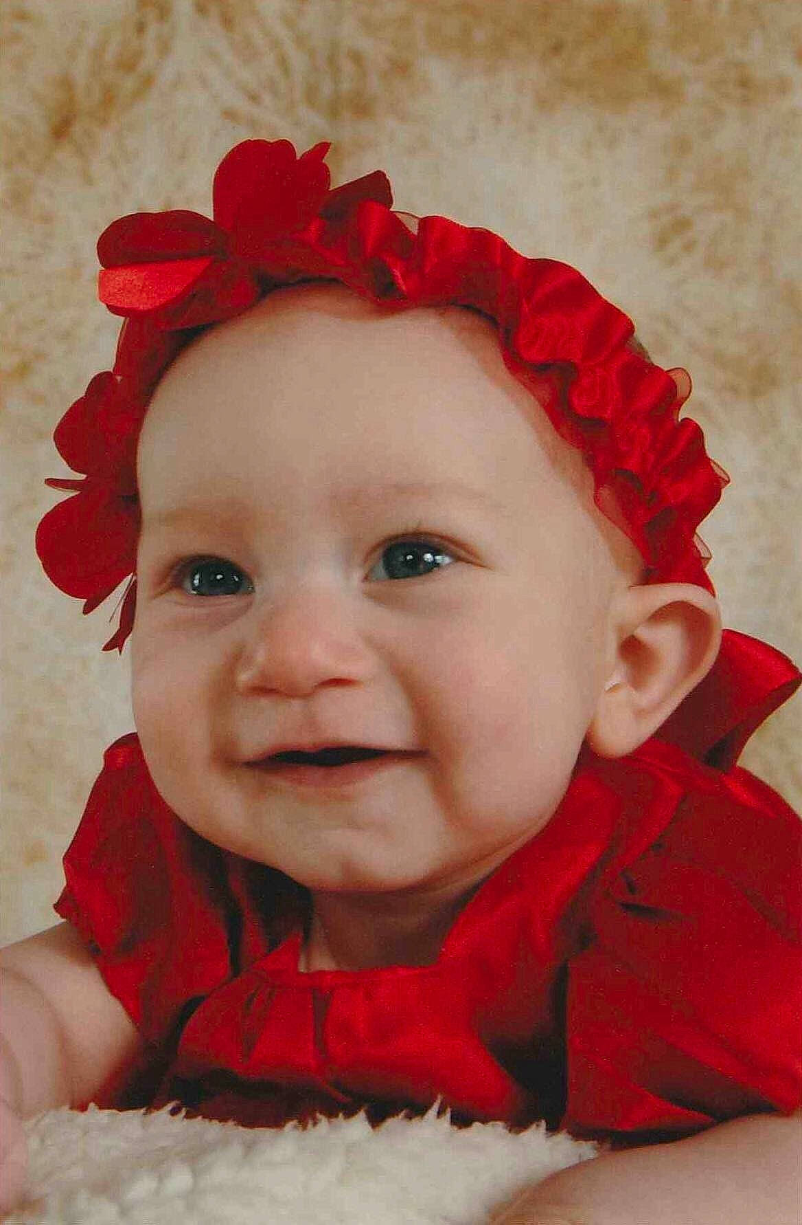 Orianna is registered to the contest to win money with this photo: cheek, child, ear, flower, girl, hair_accessory, headband, headgear, infant, laughter, lip, person, petal, red, rose_family, skin, smile, textile, toddler