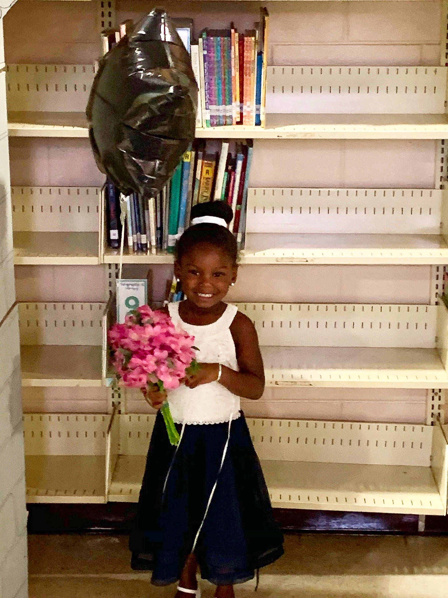 Kayla is registered to the contest to win money with this photo: child, child_model, flower, joy, person, pink, plant, room, shelf, shelving, standing, toddler