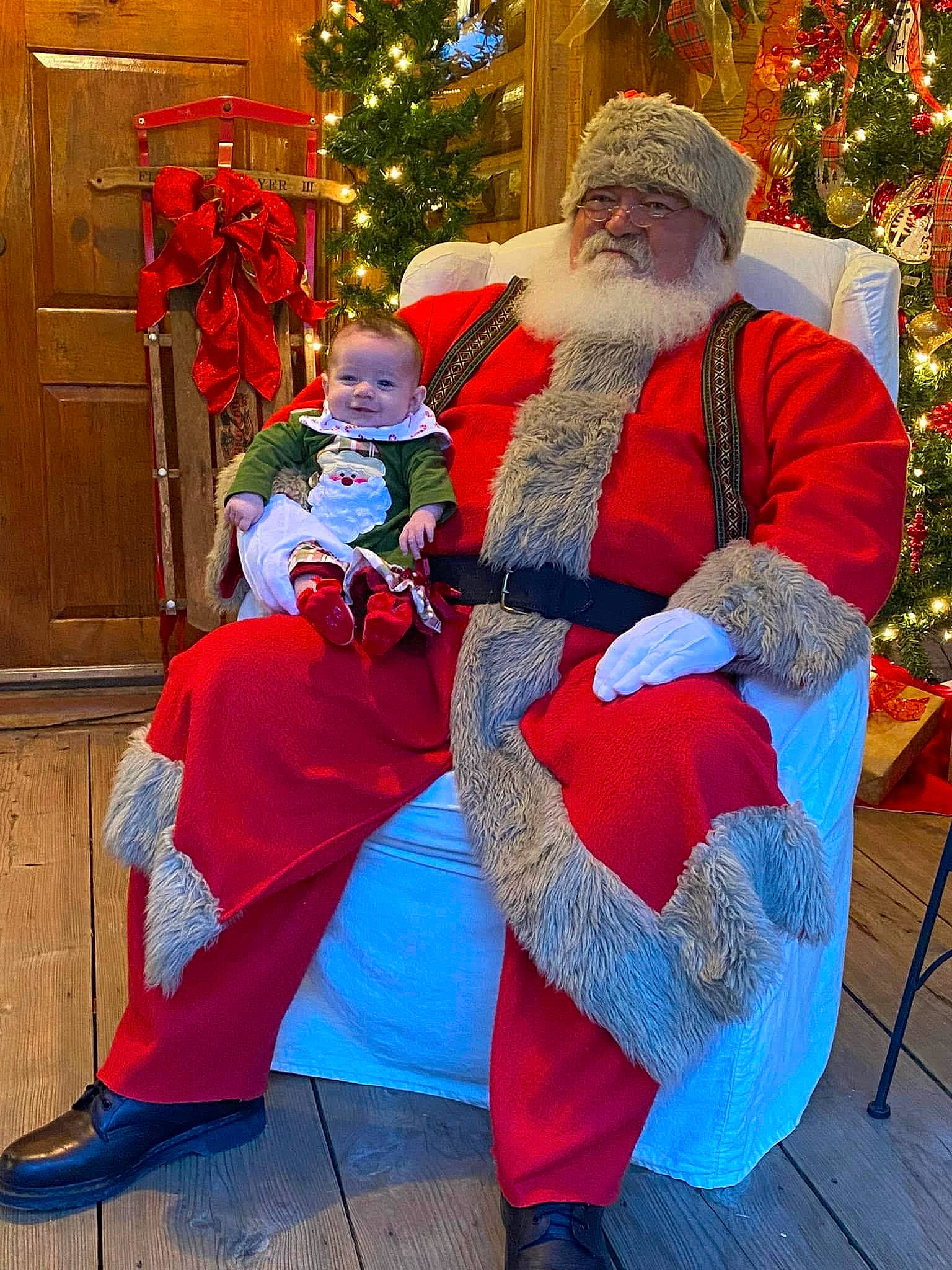 Paisley is registered to the contest to win money with this photo: beard, blue, christmas_decoration, christmas_ornament, christmas_tree, costume_hat, event, facial_expression, fun, happy, hat, headwear, joy, lap, mammal, people, person, photograph, red, santa_claus