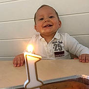 Nhaël a rejoint le concours — aidez-le/la à gagner de superbes lots ! baby, child, smile, happy, birthday, candle, cake, table, lighting, celebration, indoors, white_shirt, number_one, face, hands, young_child, front_view, cute, portrait, first_birthday