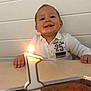 baby, child, smile, happy, birthday, candle, cake, table, lighting, celebration, indoors, white_shirt, number_one, face, hands, young_child, front_view, cute, portrait, first_birthday