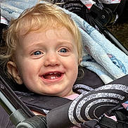 Olivia joined the competition — help win amazing prizes! toddler, child, smile, blue_eyes, blonde_hair, stroller, blanket, rainbow_pattern, baby_clothing, safety_harness, outdoor, closeup, happy, cute, portrait, infant, seat_belt, fabric, face, baby