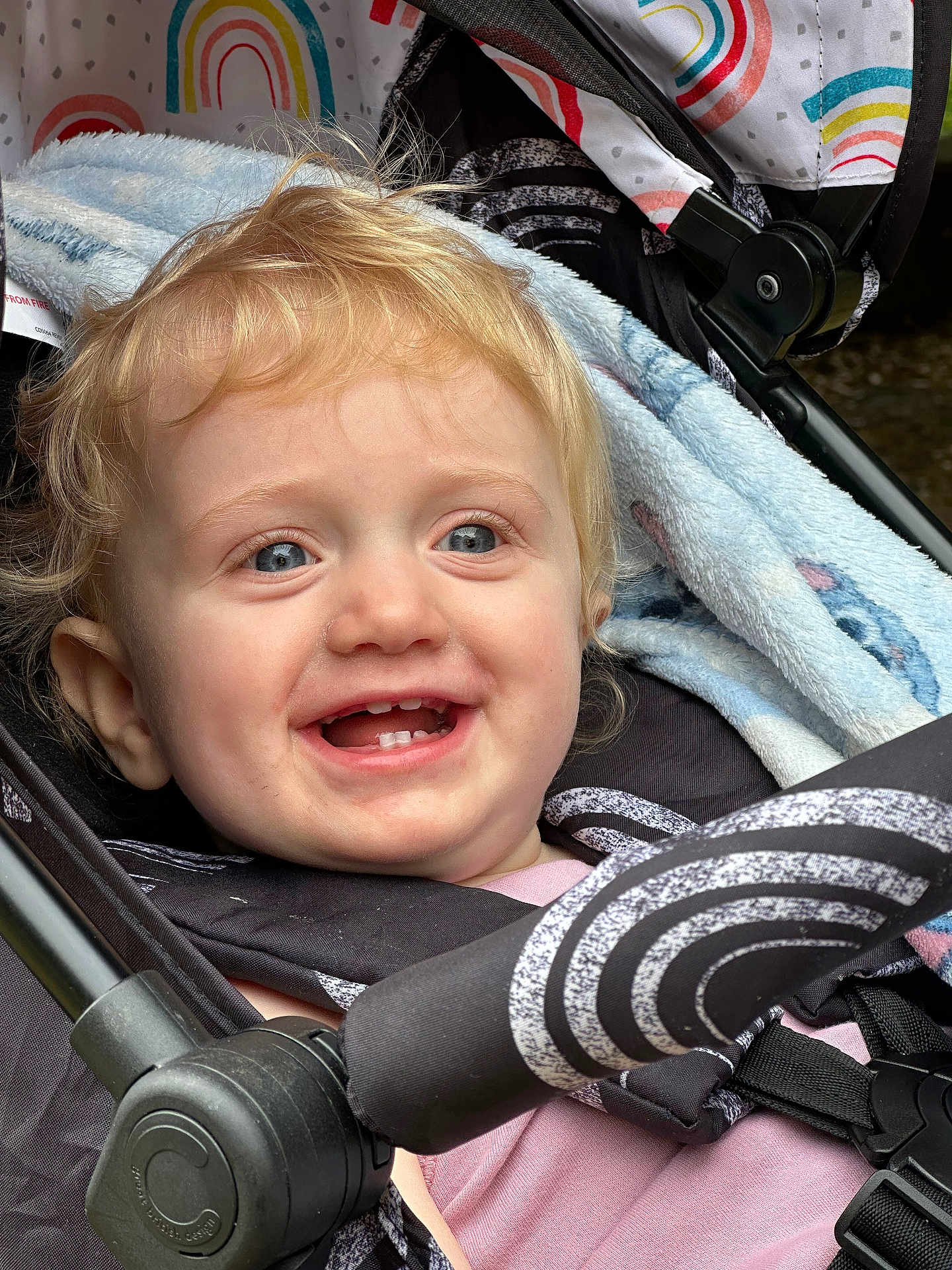 Olivia joined the competition — help win amazing prizes! toddler, child, smile, blue_eyes, blonde_hair, stroller, blanket, rainbow_pattern, baby_clothing, safety_harness, outdoor, closeup, happy, cute, portrait, infant, seat_belt, fabric, face, baby