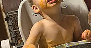 Ezra joined the competition — help win amazing prizes! baby, bare_chested, child, curly_hair, dining, eating, facial_expression, family_scene, food, high_chair, home, indoors, messy_face, orange_food, portrait, sitting, smiling, table, toddler, tray