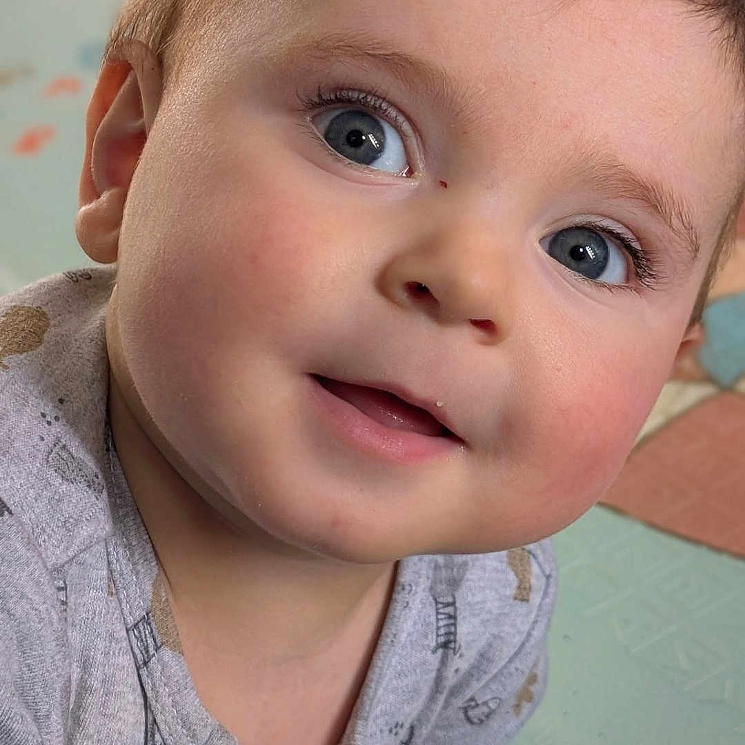 Arthur a rejoint le concours — aidez-le/la à gagner de superbes lots ! baby, infant, child, face, blue_eyes, rosy_cheeks, onesie, hand, play_mat, curious, cute, portrait, close_up, indoor, soft_lighting, young_child, smiling, expression, skin, hair