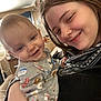 Thomas is registered to the contest to win money with this photo: baby, casual, child, clothing, cozy, cute, face, family, fun, happy, holding, home, indoor, living_room, onesie, person, portrait, smile, woman, young