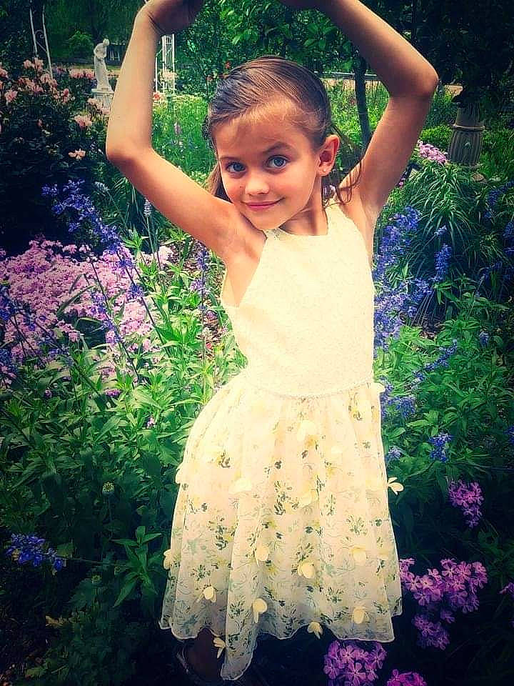 Melanie May is registered to the contest to win money with this photo: botany, facial_expression, flash_photography, flower, grass, green, hairstyle, happy, joy, leaf, light, natural_environment, nature, people_in_nature, person, petal, plant, purple, shoulder, smile