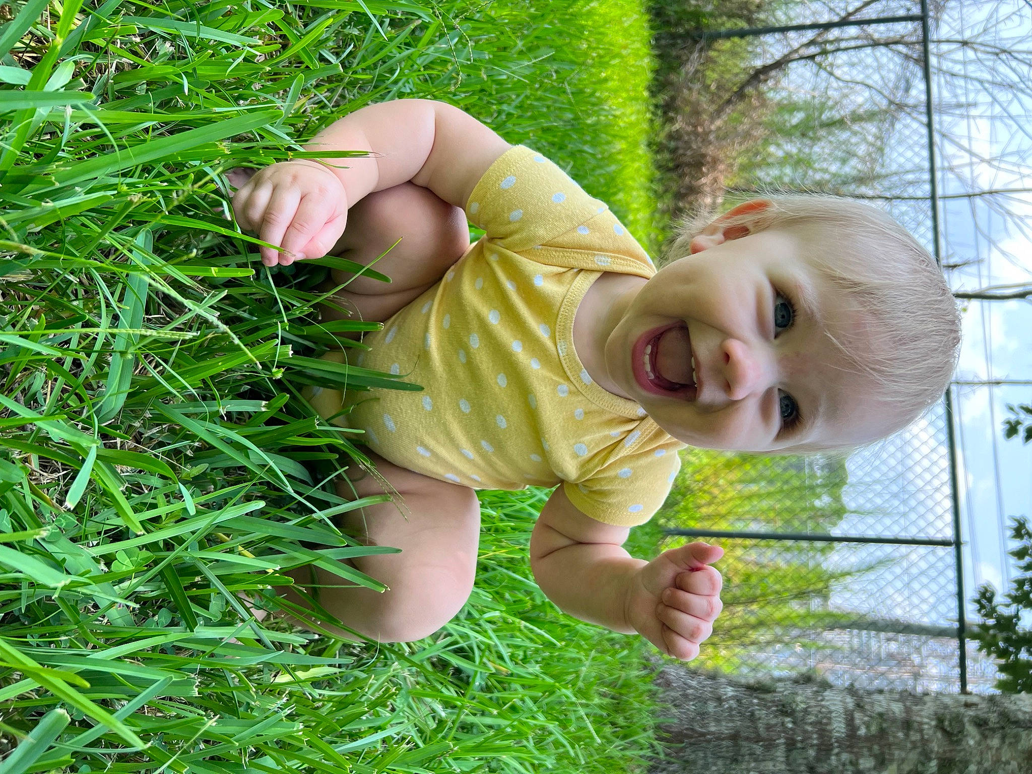 Peyton is registered to the contest to win money with this photo: baby_laughing, baby_toddler_clothing, botany, finger, grass, hand, happy, leaf, mammal, nature, nose, people_in_nature, person, plant, skin, smile, terrestrial_plant, toddler, tree, vertebrate